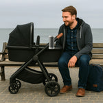 Father relaxing next to baby stroller using RockingRide automatic stroller rocker