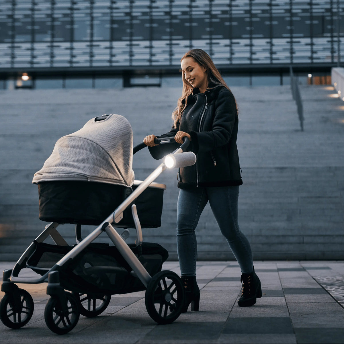 Mother pushing baby stroller at night with RockingRide stroller rocker and integrated LED light