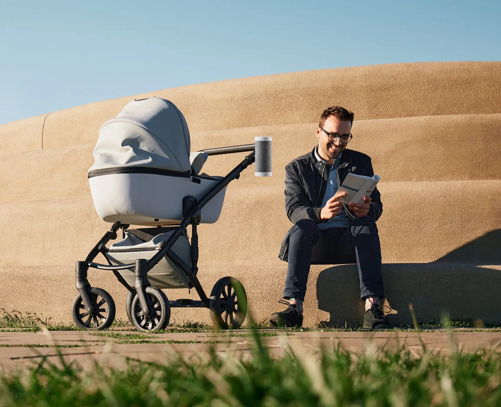 A man enjoying a peaceful moment outdoors with his baby in a stroller equipped with the RockingRide stroller rocker. The sleek design and hands-free rocking feature make parenting easier and more enjoyable.